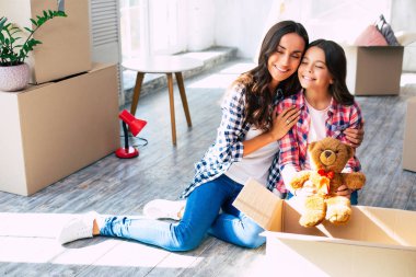 Küçük bir çocuk, güzel annesine yeni evlerinde karton kutularla yardım ediyor..
