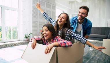 Baba yeni evinde ailesiyle oynuyor, anne ve kızı karton bir kutunun içinde gülüyorlar, hepsi coşkulu ve pozitif duygularla dolu görünüyorlar..