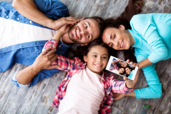 3人の幸せな若い家族が床に横たわっている — ストック写真