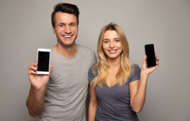 Stüdyo arka planında akıllı telefonları gösteren mutlu çift 