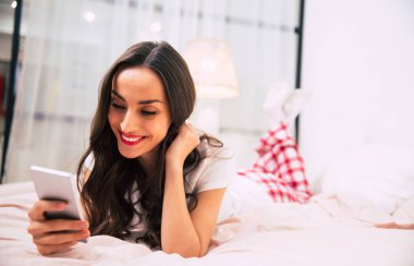 young beautiful woman using smartphone  in bedroom 