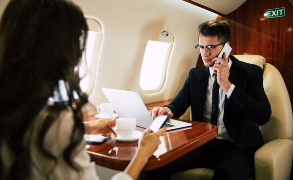 деловая пара в самолете со смартфонами

