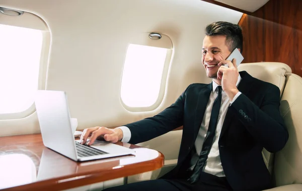 young businessman on the plane using smartphone