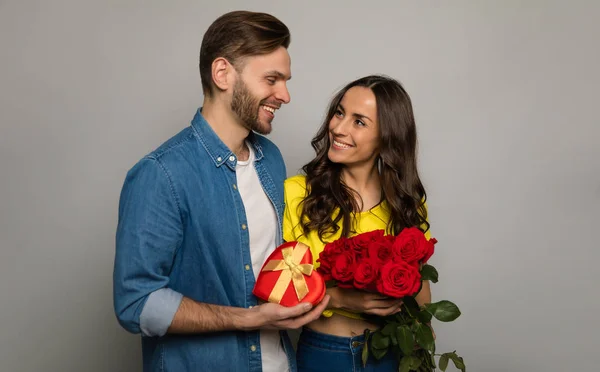 Glückliches Paar Mit Geschenk Und Blumen Auf Studiohintergrund — Stockfoto
