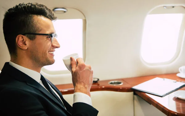 young businessman on the plane drinking tea