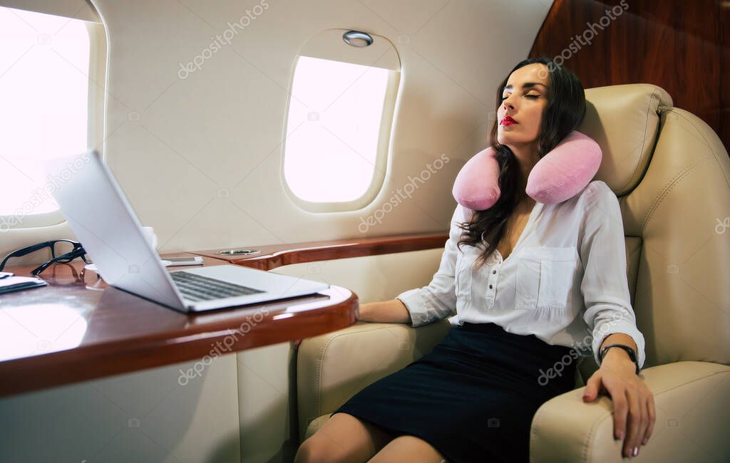 Young woman on plane with pillow 