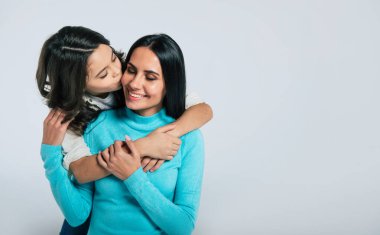Mutlu anne ve kız kucaklaşıp gülümsüyor.