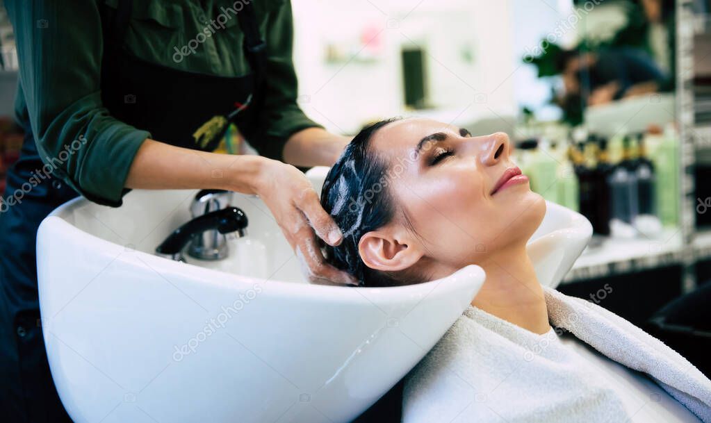 Hairdresser washing head her client. Woman in a hair salon