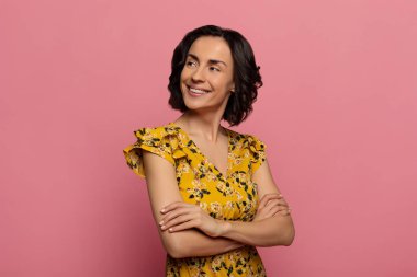 Neşeli bir bakış. Kendine güvenen, kıvırcık saçlı genç bir kızın yakın plan fotoğrafı. Sola bakıyor ve elleri bağlı gülümsüyor.. 