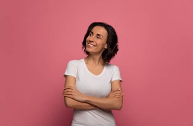 İyi bir uykudan sonra. Beyaz tişörtlü çekici kadın kollarını kavuşturmuş gülümserken sol üst köşeye bakıyor..