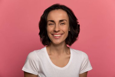 Yüzüme bak! Kısa saçlı, beyaz tişörtlü, fevkalade güzel bir esmer kızın portresi. Kameraya son derece mutlu bir şekilde bakıyor..