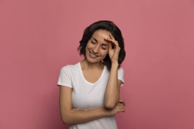 Güzellik sırları. Sol eliyle alnına dokunurken gözleri kapalı gülümseyen, beyaz tişörtlü modern bir genç kadının yakın plan fotoğrafı..