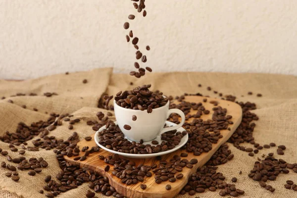 Tomber grains de café dans la tasse de porcelaine — Photo