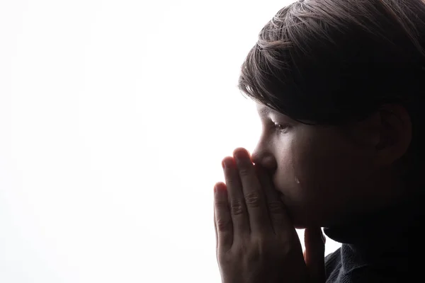 Boy praying and crying with clasped hands
