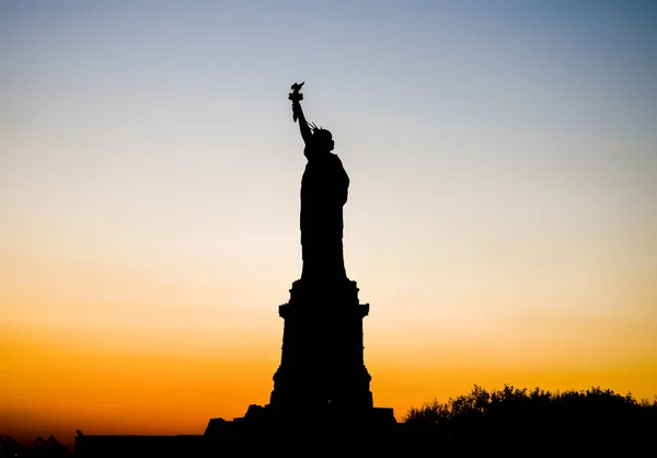 A silhueta Estátua da Liberdade contra o pôr-do-sol carmesim — Fotografia de Stock