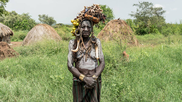 Portrait of a Mursi woman. The women of the Mursi tribe have a lip plate and iron decorations