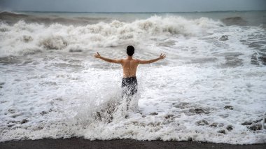 Antalya - Türkiye - 17 Ekim 2013: Bulutlu bir fırtınada deniz dalgalarına karşı duran genç adam