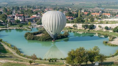 Sıcak hava balonu Pamukkale travertine, Denizli, Türkiye yakınlarındaki havuza dokunuyor