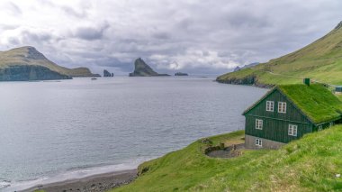 Kuzey Atlantik 'teki Faroe Adaları' nda deniz kenarında çimen çatılı bir ev.