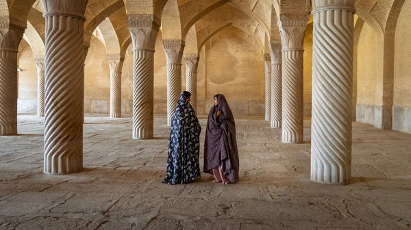 Két iráni nő beszél a Vakil mecset imatermében oszlopokkal, Shiraz, Irán — Stock Fotó