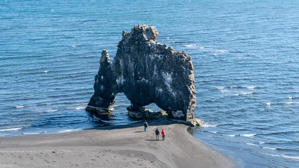 Unbekannte Touristen rund um Hvitserkur, einem spektakulären Felsen im Meer, Island. — Stockfoto