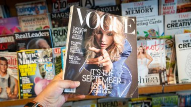 Kapağında Taylor Swift olan Vogue dergisinin bir kopyasını tutuyor.