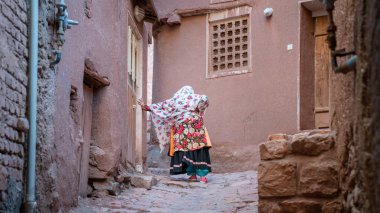 İran 'ın Abyahen şehrinde dar bir yolda geleneksel İran giysileri içinde yatan kimliği belirsiz bir kadın.
