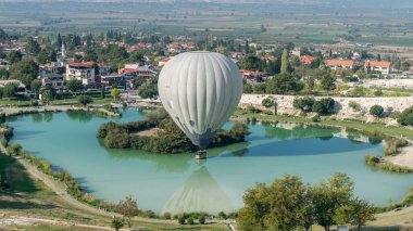 Sıcak hava balonu Pamukkale travertine, Denizli, Türkiye yakınlarındaki havuza dokunuyor