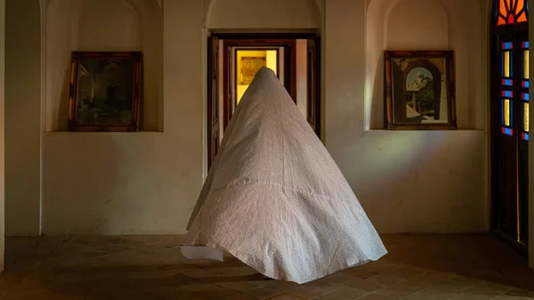 Неопознанная иранская женщина в чадре хиджаба входит в исторический дом Табатабеи Натанзи Хане в Кашане, Иран — стоковое фото