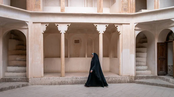 Иранская женщина в чадре хиджаба входит в исторический дом Табатабеи Натанзи Хане в Кашане, Иран — стоковое фото