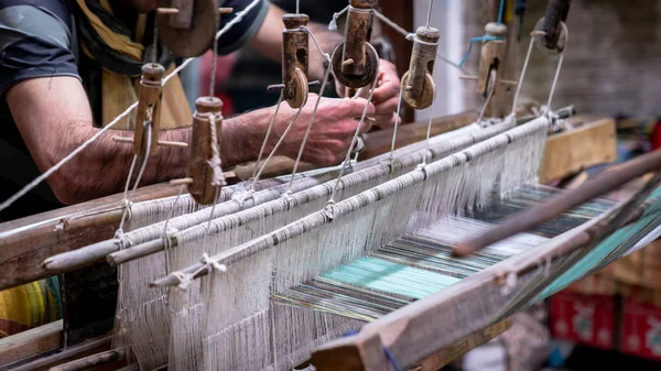 Hombre iraní haciendo una alfombra de lana en las cuerdas de algodón en el taller de alfombras — Foto de Stock
