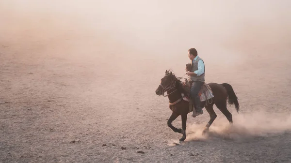 Homme chevauchant un cheval dans la poussière — Photo