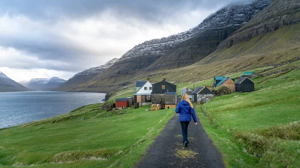 Невідома жінка, що ходить у драматичному ландшафті на Фарерських островах з традиційними будинками в північній Атлантиці. — стокове фото