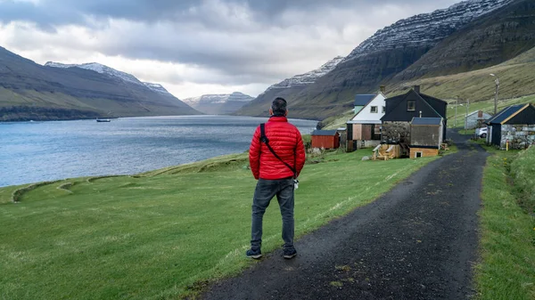 Hombre no identificado mirando el paisaje dramático en las Islas Feroe con casas tradicionales en el Atlántico norte — Foto de Stock