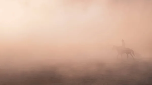 Unbekannter reitet auf Pferd in Staub und Nebel — Stockfoto