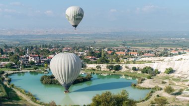 Sıcak hava balonu Pamukkale travertine, Denizli, Türkiye yakınlarındaki havuza dokunuyor