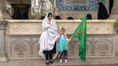 İranlı kadınlar ve kızı İran 'ın Qom kentindeki Fatima Masumeh Tapınağı' nda İslami bir bayrak taşıyorlar.