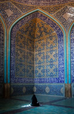 Tanımlanamayan İranlı kadın çarşaf giyip Şeyh Lotfollah Camii 'nin içinde duvarları fayanslarla dua ediyor, İsfahan, İran