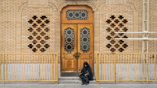 Иранская женщина сидит у двери в священном городе Кум, Иран — стоковое фото