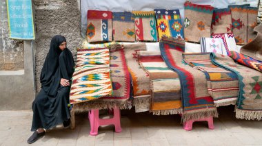 İran 'ın Şii Çarşısında kilim ve halı satan İranlı bir kadın.