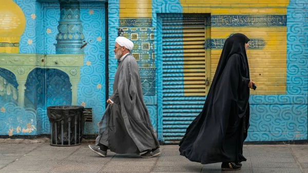 Homem e mulher iranianos de vestido preto andando em uma rua na cidade sagrada de Qom, Irã — Fotografia de Stock