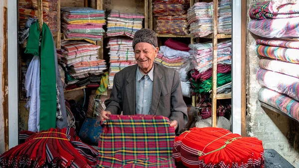Az iráni öregember nevet, textilt árul az iszfaháni bazárban, Iránban. — Stock Fotó