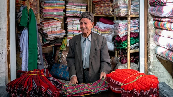 Iraanse oude man verkoopt textiel in zijn kleine winkel in Grand Bazaar van Isfahan, Iran — Stockfoto