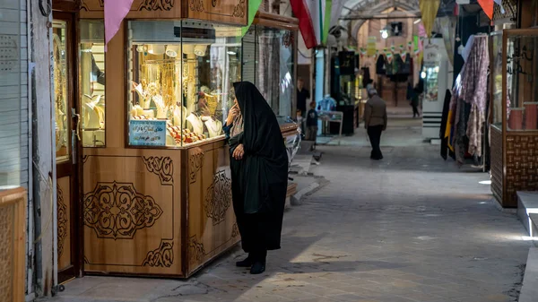 Иранская женщина смотрит на золотые аксессуары и ювелирные украшения на большом базаре в Язде, Иран — стоковое фото