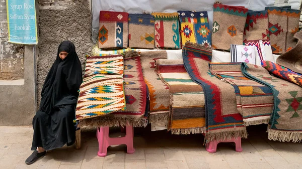 Иранская женщина продает килим и ковры в своем киоске в Большом базаре Шираза, Иран — стоковое фото