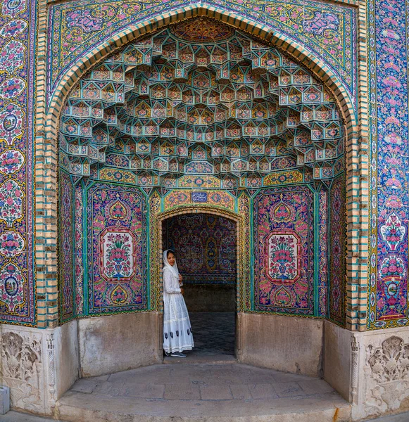 Женщина склоняется к двери с цветной плиткой Мечеть Насир аль-Мульк, Шираз, Иран — стоковое фото