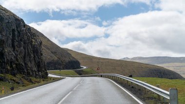 Faroe Adaları 'nda yol ve dağ sisli dramatik bir manzara..