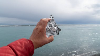 İzlanda 'nın eriyen buzuyla oluşmuş Jokulsarlon buzul gölünde bir parça buz tutan adam. Küresel ısınma ve iklim değişikliği kavramı