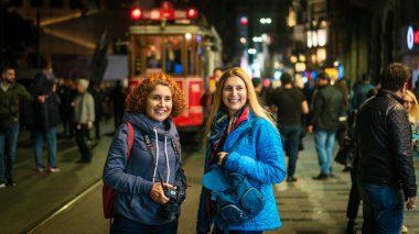 İstanbul, Türkiye - Kasım 2019: İstiklal Caddesi, Taksim Meydanı 'ndaki nostaljik tramvayın önünde mutlu turistler. Gece vakti Türkler. Fotoğraf hareketi bulanık ve bilerek ve orjinal olarak odak dışı