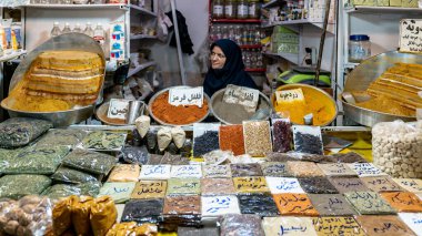 İsfahan, İran - Mayıs 2019: Tarihi pazar olan İsfahan Büyük Çarşısı 'nda çeşitli otlar ve baharatlar satan Iraklı kadın